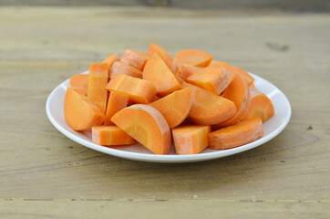 Cut carrots thick in white plate on wooden background