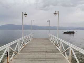 Walking path towards the lake. Lake, boat, sky and clouds.