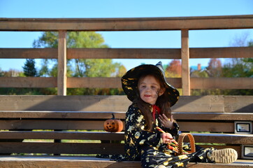 a girl in a witch suit and a black hat on the head with black Halloween make-up, zombie eating...