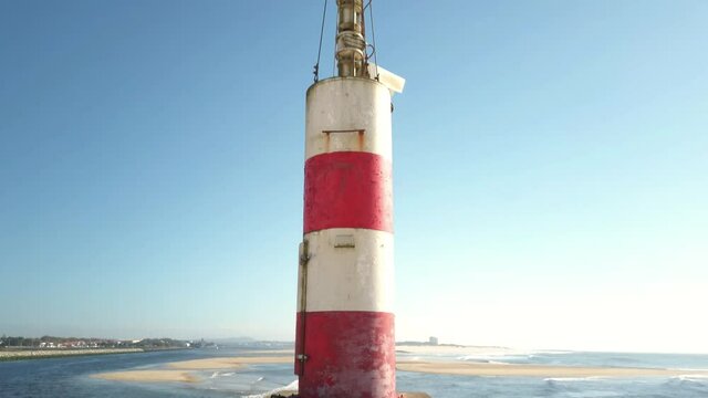 The two sides of Restinga de Ofir. The Ronca de Esposende, a red and white colored beacon alerts on the pier, Portugal.