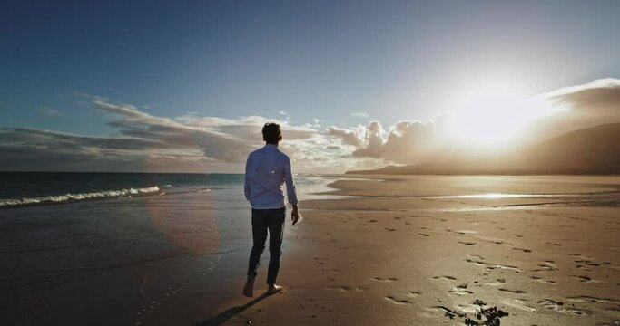 At sunset waking guy through the beach side beside the sea he have a meditation time alone