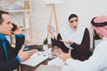  Arabs sit at a table in the office of a realtor. 