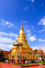Naklejka premium Ancient gold pagodaon bright blue sky background at Wat Phra That Hariphunchai woramahawihan in Lamphun of Thailand