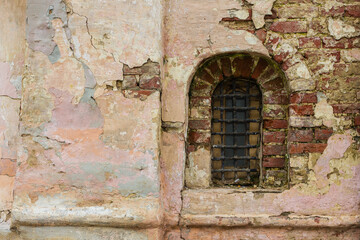 Old stone window old Russian style. Vintage window of a 16th-century Church with peeling bricks in Russia. Bars on an ancient window.