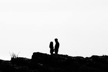 Silhouette of two lovers behind rocks