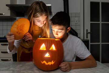 Junge und Mädchen bestaunen Ihren selbst geschnitzten Kürbis der schaurig schön in der Halloween...