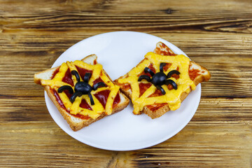 Funny sandwiches with spider and spider web for Halloween party on wooden table