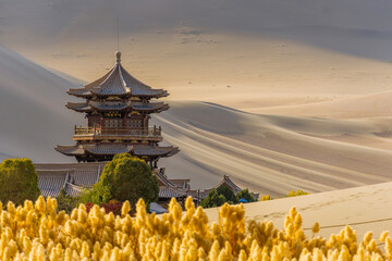 Mingyue Pavilion inside the Crescent Lake Oasis and desert background. This is a famous place part of the silk road in Dunhuang, China.