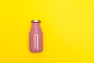 Pink glass bottle with Golden lid on yellow background with copy space. Fruit beverage with collagen or yogurt. Concept - Healthy drinks