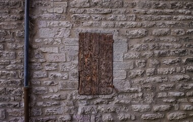 An isolated window with old wooden shutters of an abandoned medieval building with stone walls (Gubbio, Umbria, Italy, Europe)