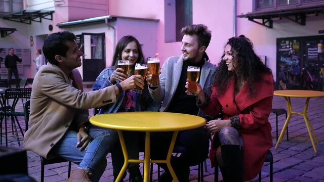 Hang out young people friends drink alcohol beer in city street bar outdoor sit at the table