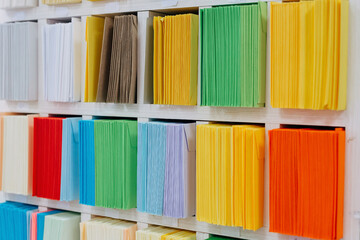 Envelopes stacks sorted on a shelf by color. Colorful mail wraps arranged in categories.