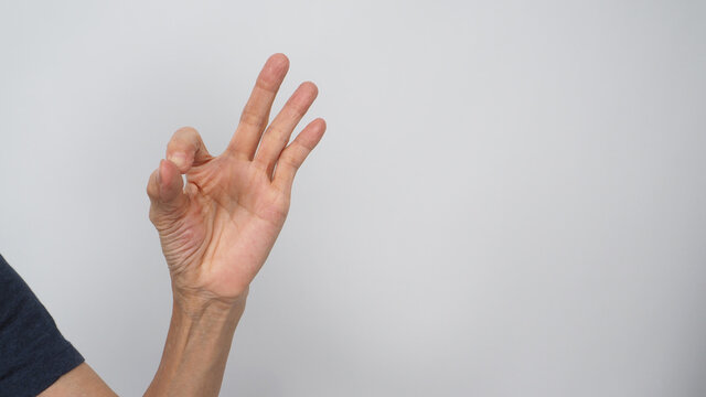 Hand Of Asian Senior Or Older Woman Is Doing A-Ok Hand Sign On White Background.