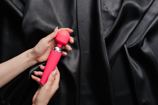 female hands in handcuffs on a dark silk sheet with a masturbator