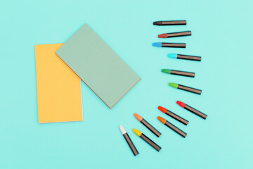 Top view of colored pastel crayons and notebook on spring for sketches. Set of multicolored chalks...