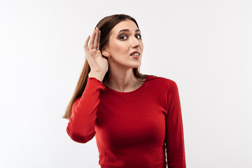 Young pretty brunette woman holding hand near ear trying to listen something. Human emotions,...