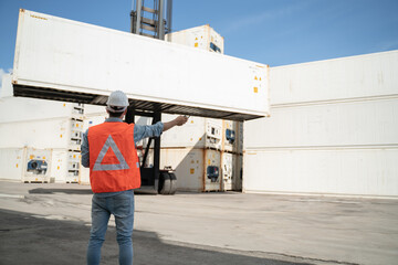 Engineer or worker man using a smartphone wearing mask and safety yellow helmet to protection for coronavirus in during concern about covid pandemic.Workers wearing protective mask working in cargo.