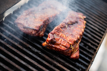grilling baby back pork ribs over flaming grill.