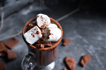 Hot chocolate and marshmallows. Cocoa in a glass goblet, cup. Dark background. Copy space.