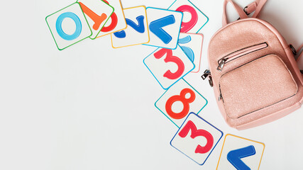 Pink school backpack with colorful training cards. Numbers. On white background with copyspace