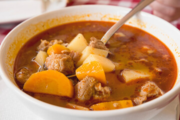 Hot meat goulash soup with paprika, potatoes and pieces of dough (dumplings) is the traditional...