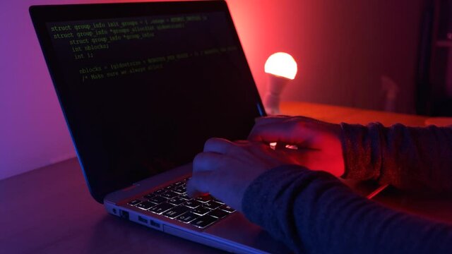 man coding with leptop burning neon lights at night