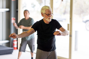 Fototapeta na wymiar Group of elderly senior people practicing Tai chi class in age care gym facilities.