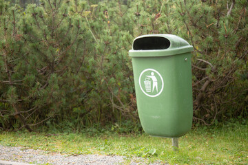 Waste bin in front of conifer trees