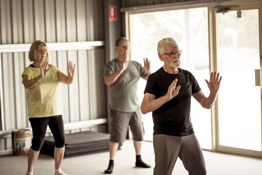 Group Of Elderly Senior People Practicing Tai Chi Class In Age Care Gym Facilities.