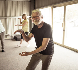 Group of elderly senior people practicing Tai chi class in age care gym facilities.