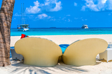 Fototapeta na wymiar Beach chairs on the white sand on the shore of a beautiful tropical sea.