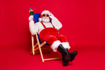 Portrait of his he nice handsome cheery bearded fat Santa father hipster guy sitting in chair relax chill out spending weekend leisure isolated bright vivid shine vibrant red color background