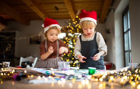 Portrait of small girl and boy indoors at home at Christmas, doing art and craft.