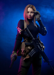 a woman in military airsoft uniform with an American automatic rifle and pistol on a dark background