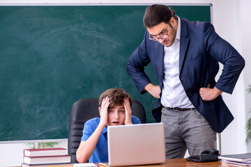 Young male teacher and schoolboy in the classroom