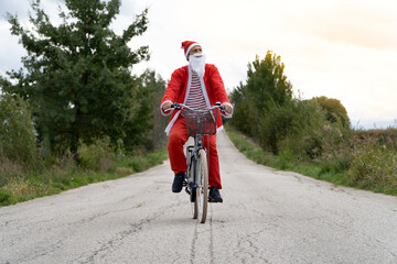 Santa Claus riding his bike on the street.