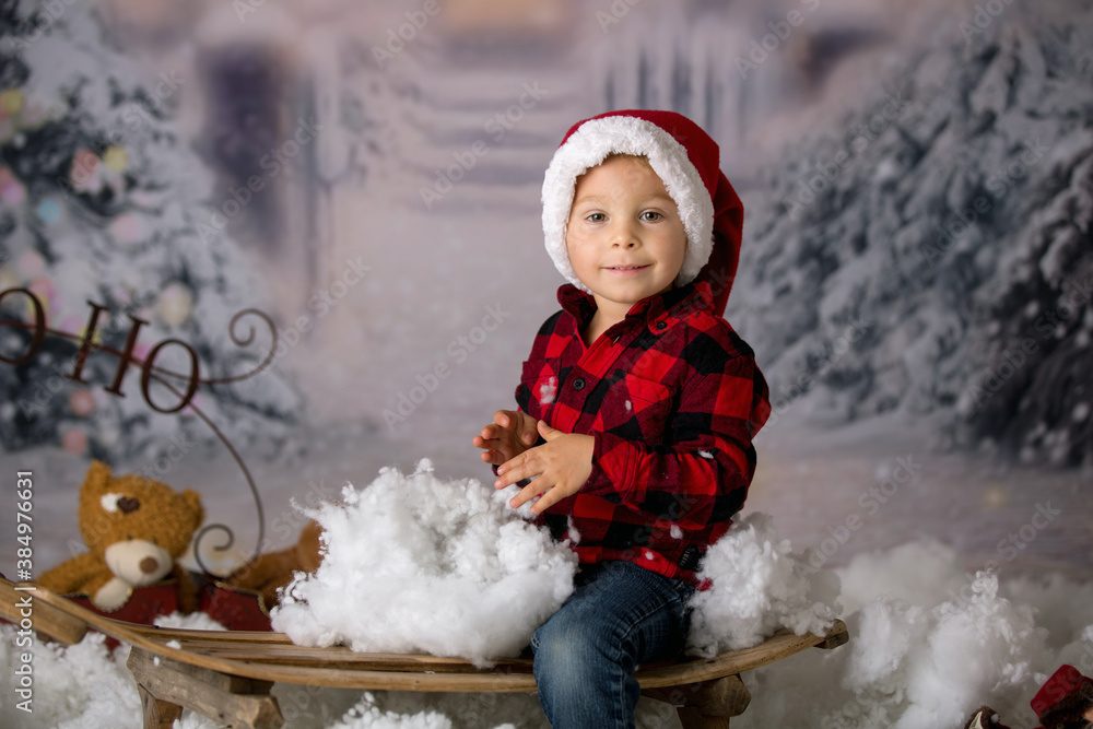 Wall mural Cute toddler boy with winter outfit, playing in the snow, christmas shot