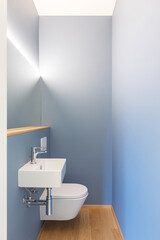 Front view of modern light blue bathroom with sink, mirror and led light