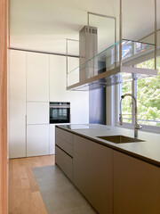 Modern kitchen with suspended hood, large sink, oven and wooden worktop.