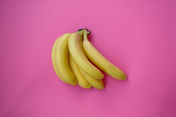 Single banana on a pink background with strong shadow. lot of bananas