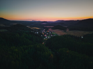 Fototapeta na wymiar Luftaufnahme von einem Dorf nach Sonnenuntergang in hügeliger Landschaft 