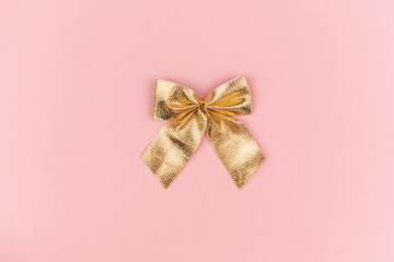 Golden Christmas small bow on pink background, new year decor, gift 2021