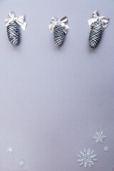 Christmas and New Year concept festive composition silver cones, bows and snowflakes on gray background copy space