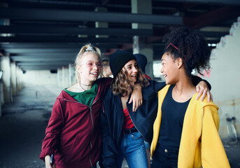 Group of teenagers girl gang standing indoors in abandoned building, hanging out.