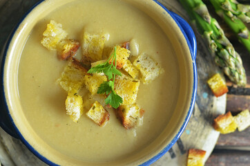 Cream soup of broccoli and asparagus with croutons on a wooden background