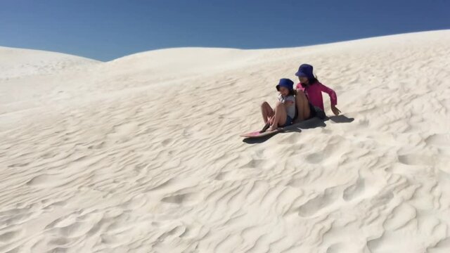 Sisters having fun sliding Lancelin sand dunes near Lancelin Western Australia