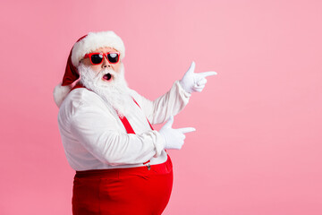 Profile side photo of astonished santa claus point index finger copyspace x-mas ads wear sunglass headwear suspenders headwear isolated over pastel color background