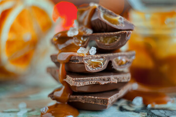 Macro chocolate pieces with caramel and sea salt against holiday background and dried oranges
