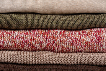 Stack folded colorful knitted sweaters background, close up