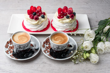 Pavlova meringue cake with cream and raspberries, blueberries, strawberries, currants. A cup of coffee, eustoma.